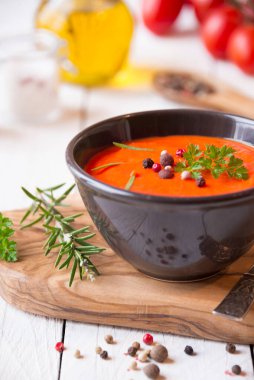 Beyaz ahşap üzerinde taze domatesli bir kasede domates çorbası.
