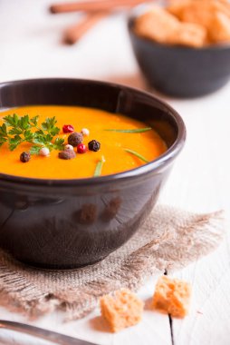 Kabak çorbası ve beyaz ahşap arka planda kızarmış ekmek.