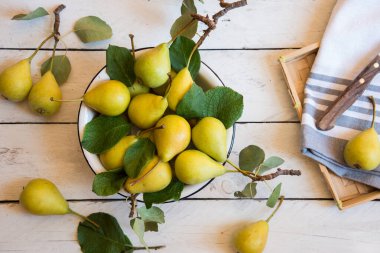 Beyaz ahşap arka planda yaprakları olan taze organik armutlar.