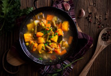Siyah ahşap arka planda maydanozlu sebze çorbası.