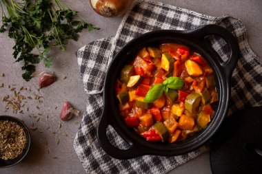 Siyah bir tencerede otlarla çeşitli sebzeler pişirdim.