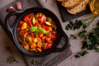 Siyah bir tencerede otlarla çeşitli sebzeler pişirdim.