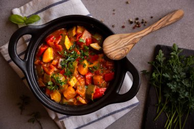 Siyah bir tencerede otlarla çeşitli sebzeler pişirdim.