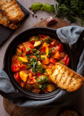 Siyah bir tencerede otlarla çeşitli sebzeler pişirdim.