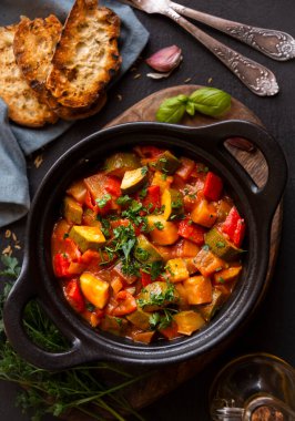 Siyah bir tencerede otlarla çeşitli sebzeler pişirdim.