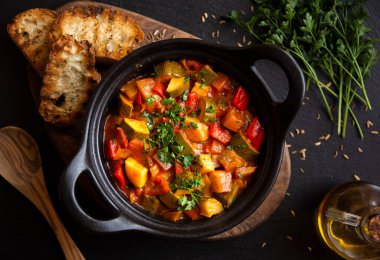 Siyah bir tencerede otlarla çeşitli sebzeler pişirdim.