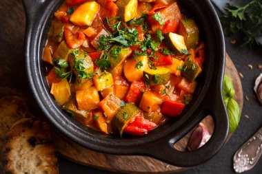 Siyah bir tencerede otlarla çeşitli sebzeler pişirdim.