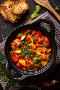 Siyah bir tencerede otlarla çeşitli sebzeler pişirdim.