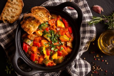 Siyah bir tencerede otlarla çeşitli sebzeler pişirdim.