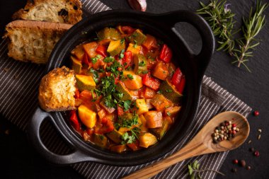 Siyah bir tencerede otlarla çeşitli sebzeler pişirdim.