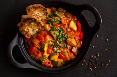 Siyah bir tencerede otlarla çeşitli sebzeler pişirdim.