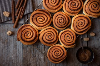 Koyu ahşap arka planda taze tarçınlı çörekler.