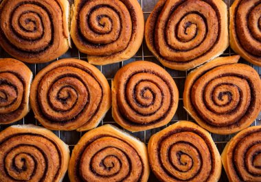 Koyu ahşap arka planda taze tarçınlı çörekler.