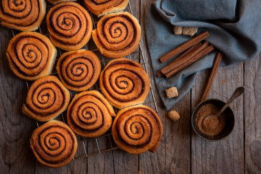 Koyu ahşap arka planda taze tarçınlı çörekler.