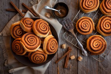 Koyu ahşap arka planda taze tarçınlı çörekler.