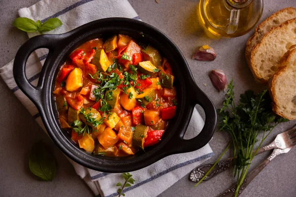 Cooked various vegetables with herbs in a black cooking pot