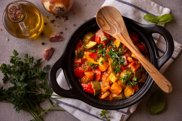 Cooked various vegetables with herbs in a black cooking pot