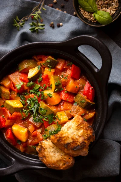 Cooked various vegetables with herbs in a black cooking pot