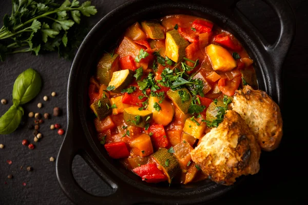 Siyah bir tencerede otlarla çeşitli sebzeler pişirdim.