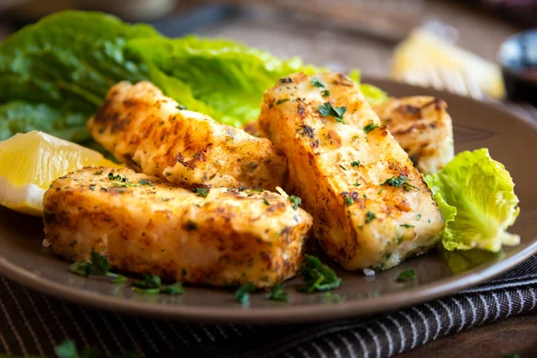 Cooked fish fillet with lemon and lettuce