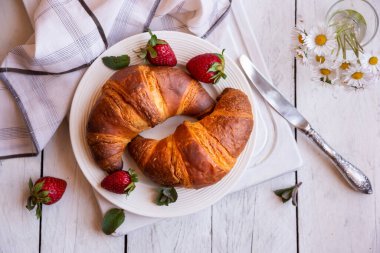 Beyaz ahşap üzerinde kahvaltı için taze kruvasanlar.
