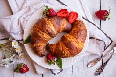 Beyaz ahşap üzerinde kahvaltı için taze kruvasanlar.