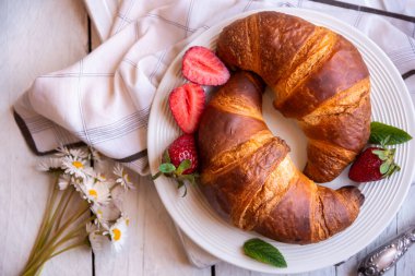Beyaz ahşap üzerinde kahvaltı için taze kruvasanlar.