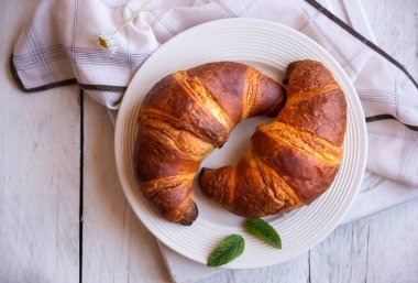 Beyaz ahşap üzerinde kahvaltı için taze kruvasanlar.