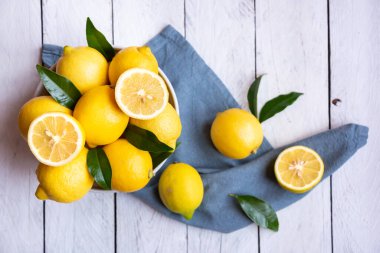 Taze ve olgun limonlar ve beyaz ahşap yapraklar.