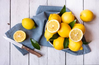 Taze ve olgun limonlar ve beyaz ahşap yapraklar.