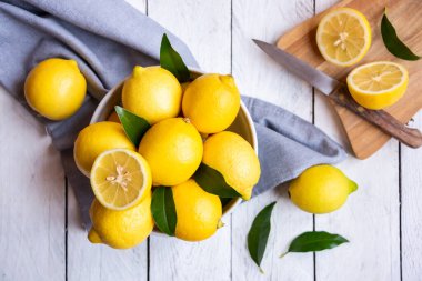 Taze ve olgun limonlar ve beyaz ahşap yapraklar.