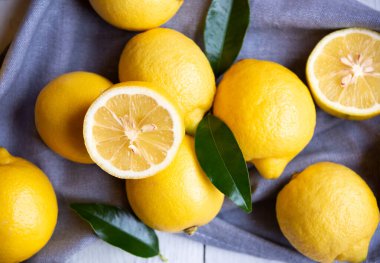 Taze ve olgun limonlar ve beyaz ahşap yapraklar.