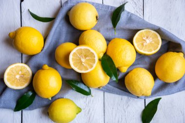 Taze ve olgun limonlar ve beyaz ahşap yapraklar.