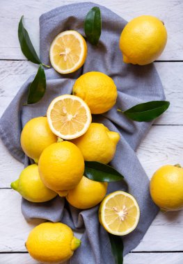 Taze ve olgun limonlar ve beyaz ahşap yapraklar.