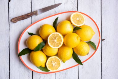 Taze ve olgun limonlar ve beyaz ahşap yapraklar.