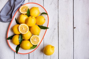 Taze ve olgun limonlar ve beyaz ahşap yapraklar.