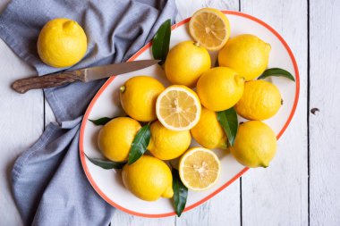 Taze ve olgun limonlar ve beyaz ahşap yapraklar.
