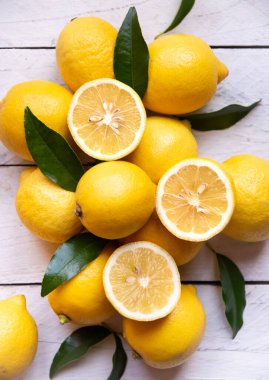 Taze ve olgun limonlar ve beyaz ahşap yapraklar.