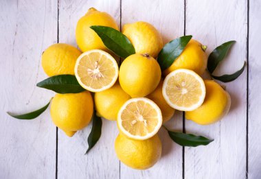 Taze ve olgun limonlar ve beyaz ahşap yapraklar.