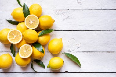 Taze ve olgun limonlar ve beyaz ahşap yapraklar.