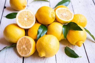 Taze ve olgun limonlar ve beyaz ahşap yapraklar.