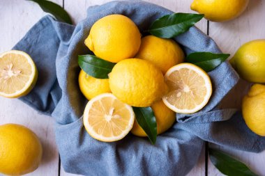 Taze ve olgun limonlar ve beyaz ahşap yapraklar.