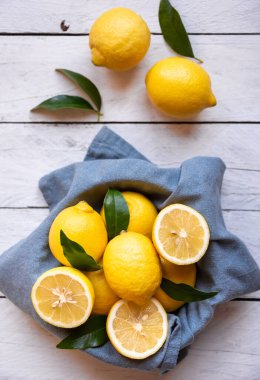 Taze ve olgun limonlar ve beyaz ahşap yapraklar.