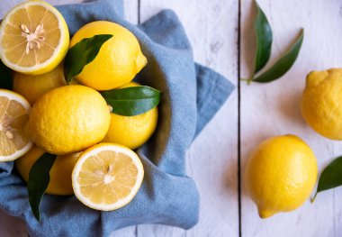 Taze ve olgun limonlar ve beyaz ahşap yapraklar.