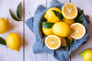 Taze ve olgun limonlar ve beyaz ahşap yapraklar.