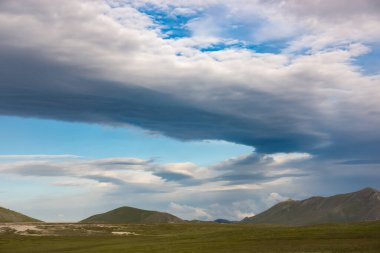 Dağların üzerinde dramatik gökyüzü olan manzara