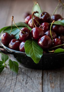 Beyaz kasede yaprakları olan taze kiraz meyvesi.