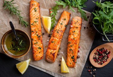 Pişmiş somon balığı fileto, otlar, limon ve sebzeler.