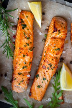 Pişmiş somon balığı fileto, otlar, limon ve sebzeler.