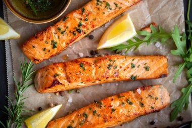 Pişmiş somon balığı fileto, otlar, limon ve sebzeler.